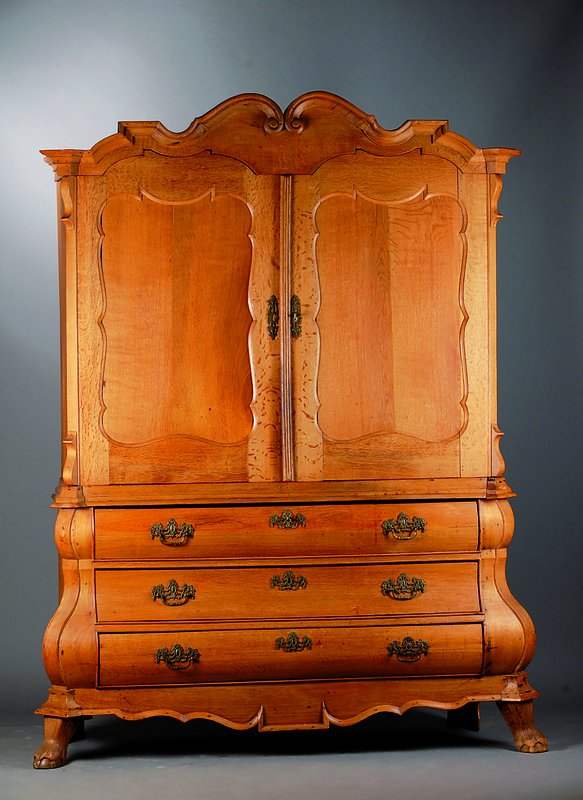 Schrank, Holland, um 1770/80, Eiche, Unterteil 3-schübig, bombiert, Oberteil 2 -türig, allseitig geschweift, reich verzierte Beschl., Tatzenfüße, ...