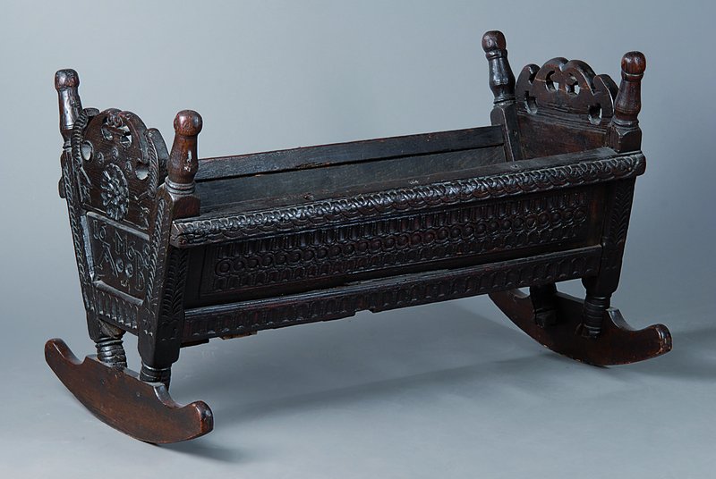 Wiege, 18. Jh., Eiche, unter Verwendung alter Teile, rest., reiche Schnitzereien, Altersschäden, schwundrissig, ca. 60x97x49 cm