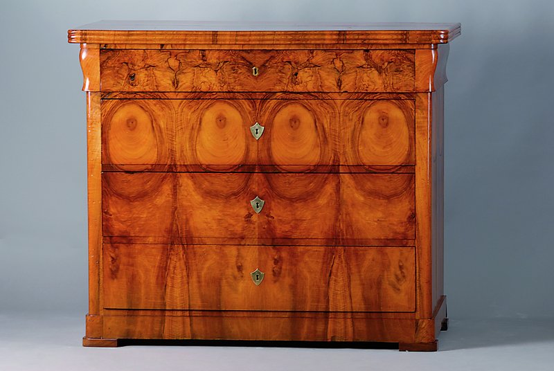 Biedermeierkommode, um 1850, Nussbaum/Wurzelfurnier, Platte 4-fach gesp. verlegt, 4-schübig, einfache Bronzebeschl., abgerundete Ecken, rest., l. ...
