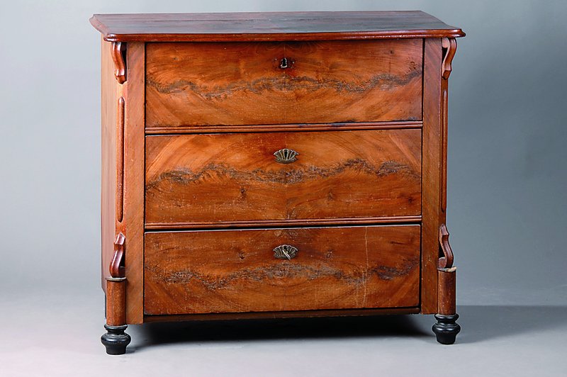 Kommode, um 1860, Pyramidenmahagonifurnier, teils gesp. verlegt, 3-schübig, 1 Beschl. fehlt, Platte geschweift, Leisten teils besch., schwundrissig, ...