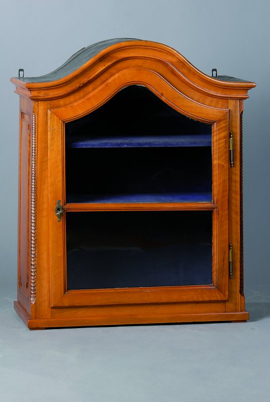 Hängeschrank, um 1820/30, Nußbaum, 1-türig verglast, Lisenen m. Schuppendekor, 2 Einlegebretter, Kopf geschweift, Gebr.-Sp., ca. 84x68x32 cm