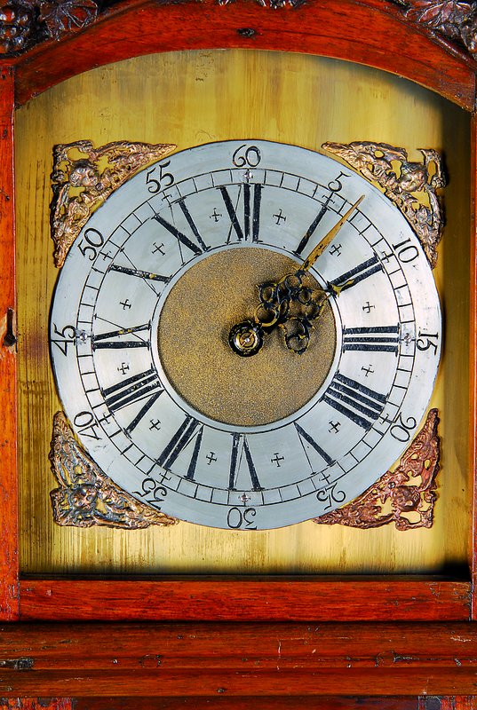 Detail a: Standuhr, um 1770, Nußbaum/Eiche verziert und geschnitzt, Sockel gekürzt, in Türe Maskeronenpaar, alter Wurmbefall, orig. Beschläge, im Giebel ...