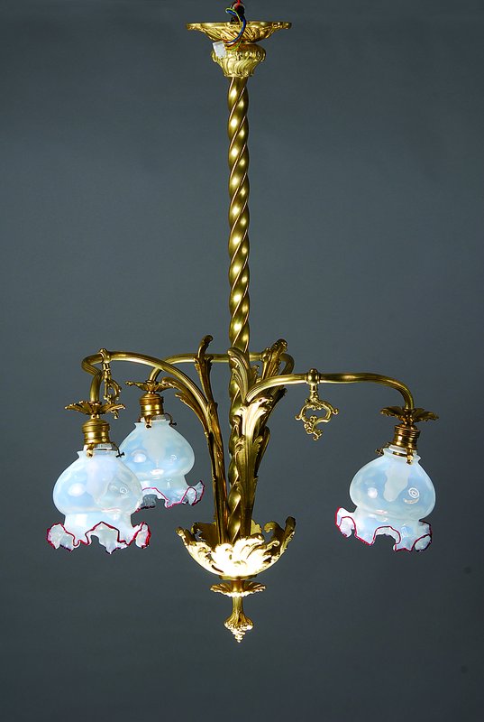 Deckenlampe, Frankreich, um 1890, Gelbgußmonturen mit in sich gedrehtem Mittelstab und drei gebogenen Armen mit Milchglasschirmen mit rotem Rand, ...