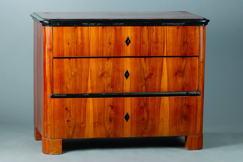 Kommode, Biedermeierstil, unter Verwendung alter Teile um 1830/40, Kirschbaumfurnier, 3 -schübig, Zierleisten geschwärzt, abgerundete Ecken, ...