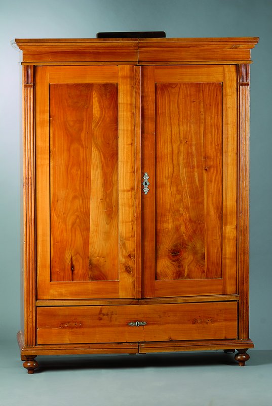 Kleiderschrank, wohl Schwarzwald, um 1880/90, Kirschbaum/Esche und Birnenholz, 2-türig, Fußschublade, sog. Spaltschrank, Beschläge sek., Kopf ...