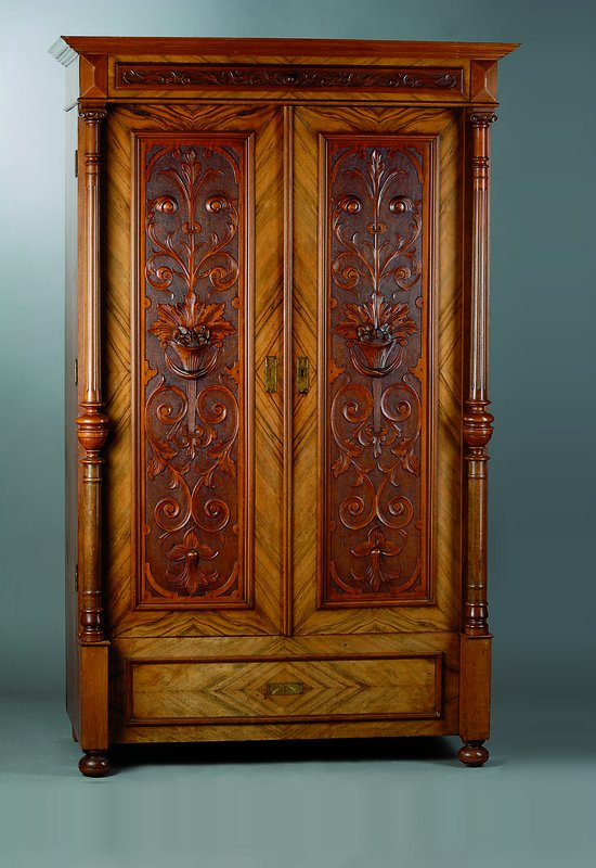 Gründerzeitschrank, um 1880, Nußbaum/Wurzelnußfurnier, 2-türig, Fußschublade, Inlets m. reicher floraler Schnitzerei, Lisenen m. Säulen, diese ...