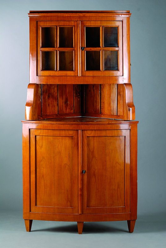 Eckvitrine, im Biedermeierstil, Kirschbaumfurnier, unter Verwendung alter Teile, Unterteil 2-türig, Oberteil 2-türig verglast u. versprosst, ...