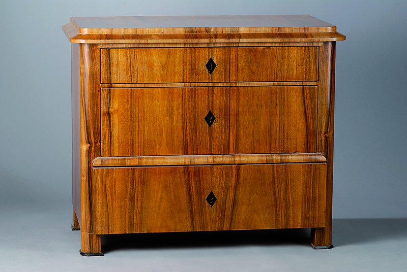 Kommode, Biedermeier, um 1830/40, Nußbaum, 3-schübig, abgerundete Ecken, l. verzogen, Teile ergänzt, ein Furnierstück fehlt, Gebr. -Sp., ca. ...