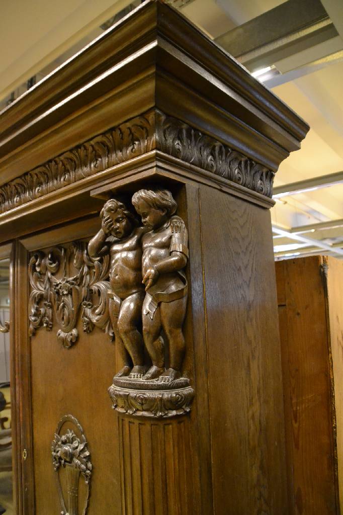 Detail b: Bücherschrank, deutsch, um 1910, Eiche massiv, aufwendige Schnitzereien, Lisenen mit vollplastischen Putti, Kopf vielfach getreppt,3-türig, 1 Tür ...
