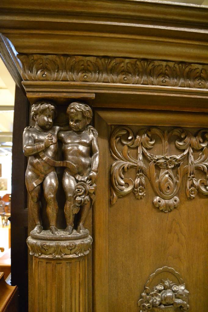 Detail e: Bücherschrank, deutsch, um 1910, Eiche massiv, aufwendige Schnitzereien, Lisenen mit vollplastischen Putti, Kopf vielfach getreppt,3-türig, 1 Tür ...