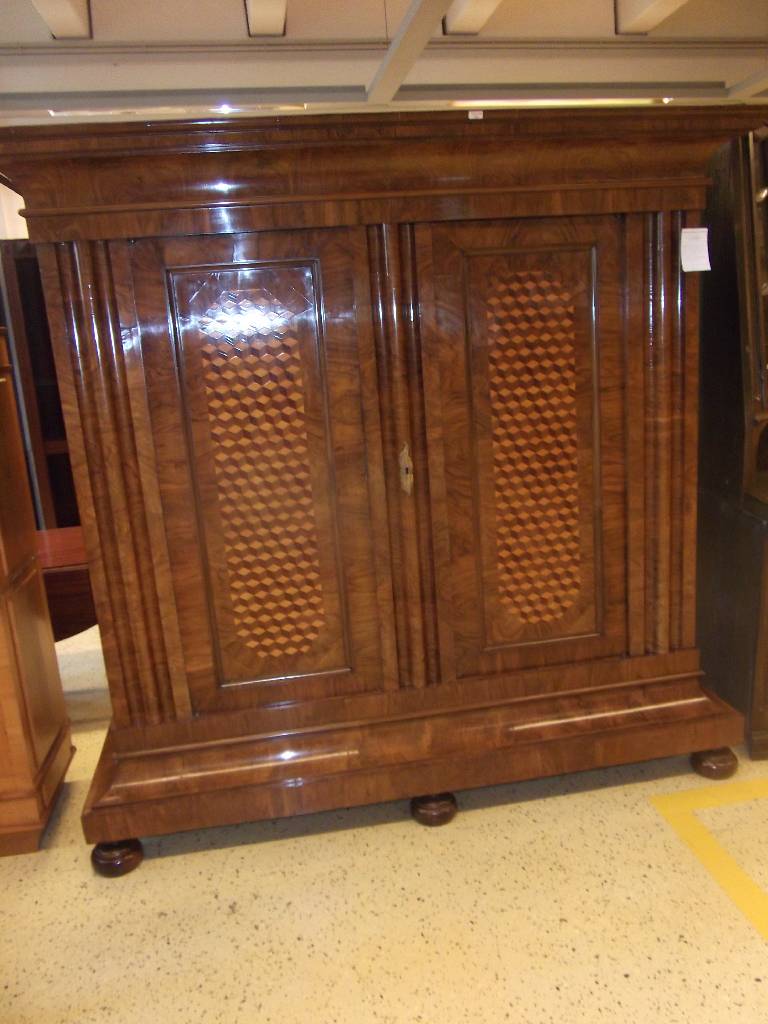 Detail a: Wellenschrank, 18. Jh., Front mit lebendigem Wurzelnussfurnier, Seiten Nussbaum, Kopf in stiltypischem Cavetto-Gesims (Hohlkehle) 3-fach getreppt, ...