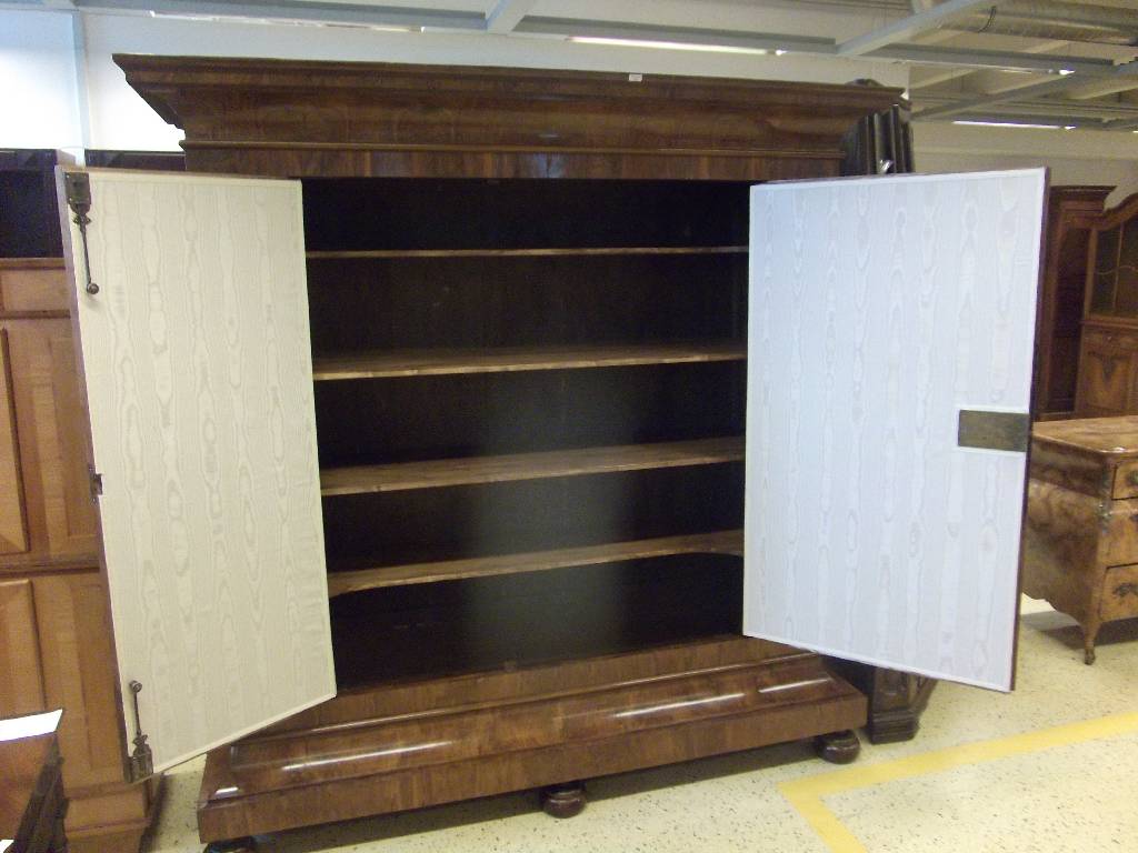 Detail b: Wellenschrank, 18. Jh., Front mit lebendigem Wurzelnussfurnier, Seiten Nussbaum, Kopf in stiltypischem Cavetto-Gesims (Hohlkehle) 3-fach getreppt, ...
