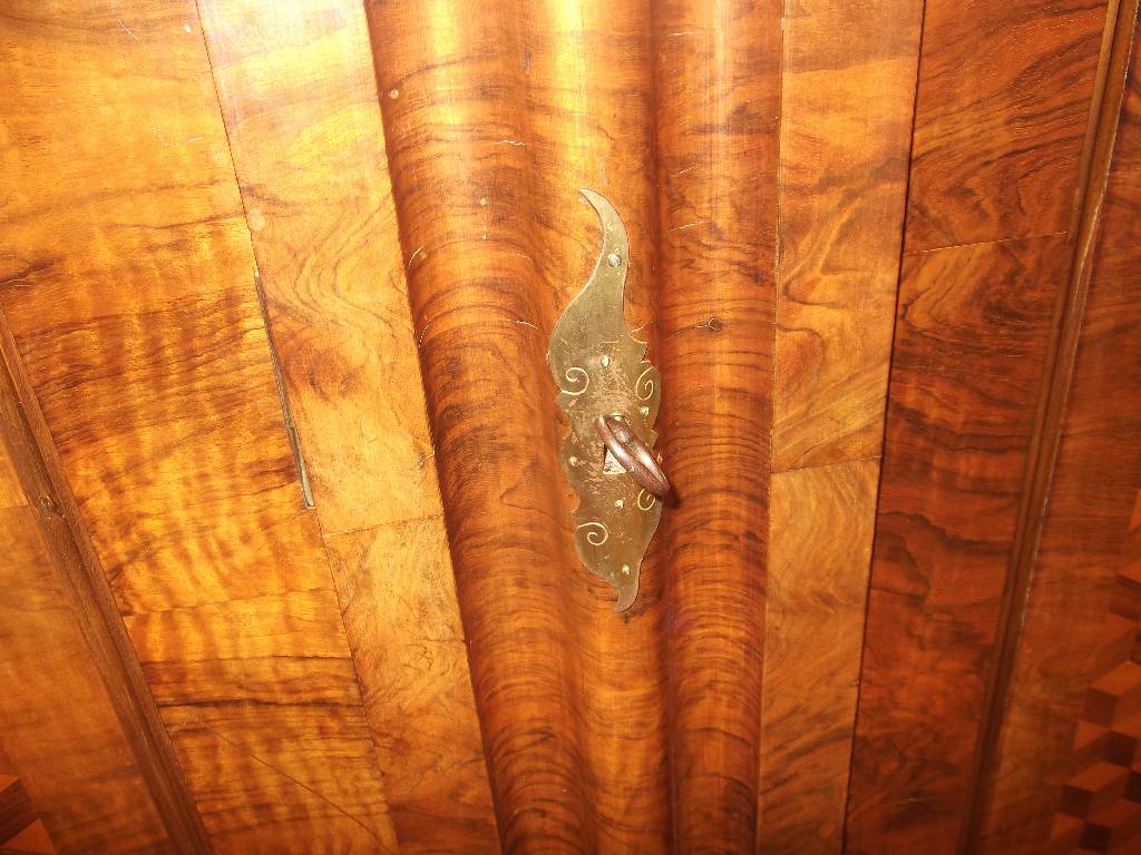 Detail f: Wellenschrank, 18. Jh., Front mit lebendigem Wurzelnussfurnier, Seiten Nussbaum, Kopf in stiltypischem Cavetto-Gesims (Hohlkehle) 3-fach getreppt, ...