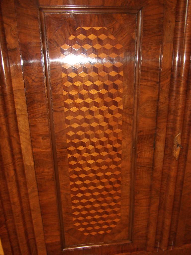 Detail g: Wellenschrank, 18. Jh., Front mit lebendigem Wurzelnussfurnier, Seiten Nussbaum, Kopf in stiltypischem Cavetto-Gesims (Hohlkehle) 3-fach getreppt, ...