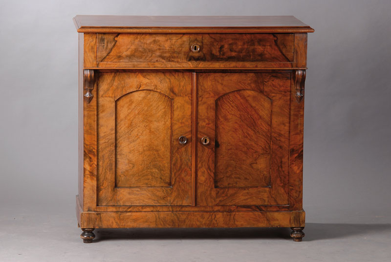 Kommode, um 1890, Wurzelnussfurnier gespiegelt verlegt, Korpus Weichholz, Platt e 3-fach getreppt, Front 1-schübig u. 2-türig, Türen je einfach ...