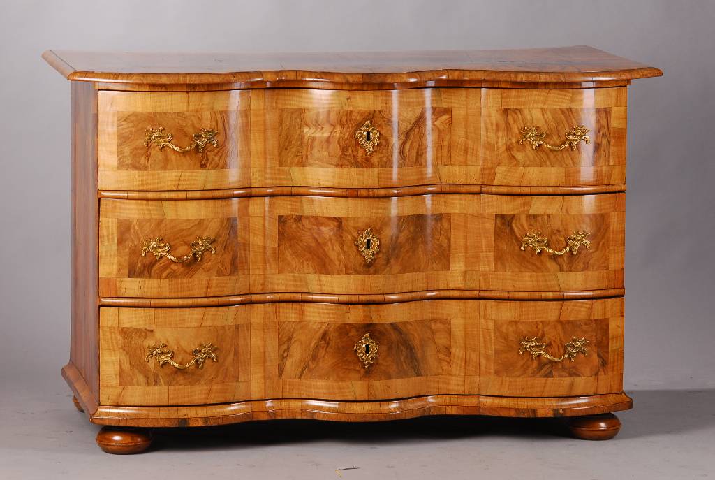 Barockkommode, deutsch um 1750, Wurzelnussfurnier, Nussholz quer angeleimt, 3 -fach geschweift und doppelt gekröpft, 3- schübig, Beschläge sek., ...