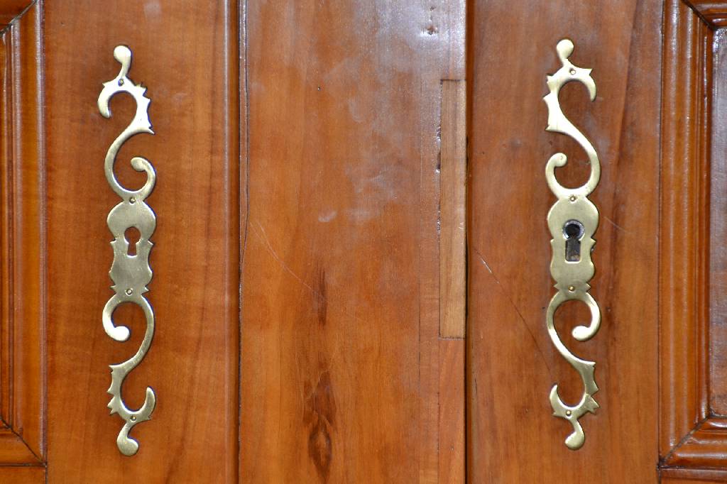 Detail a: Louis-Seize-Schrank, Pfalz/Elsaß, ausgehendes 18. Jh., Birnen-/Kirschholz, Kopf 4-fach getreppt mit Hohlkehle, Türen u. Seiten je 3- fach mit ...