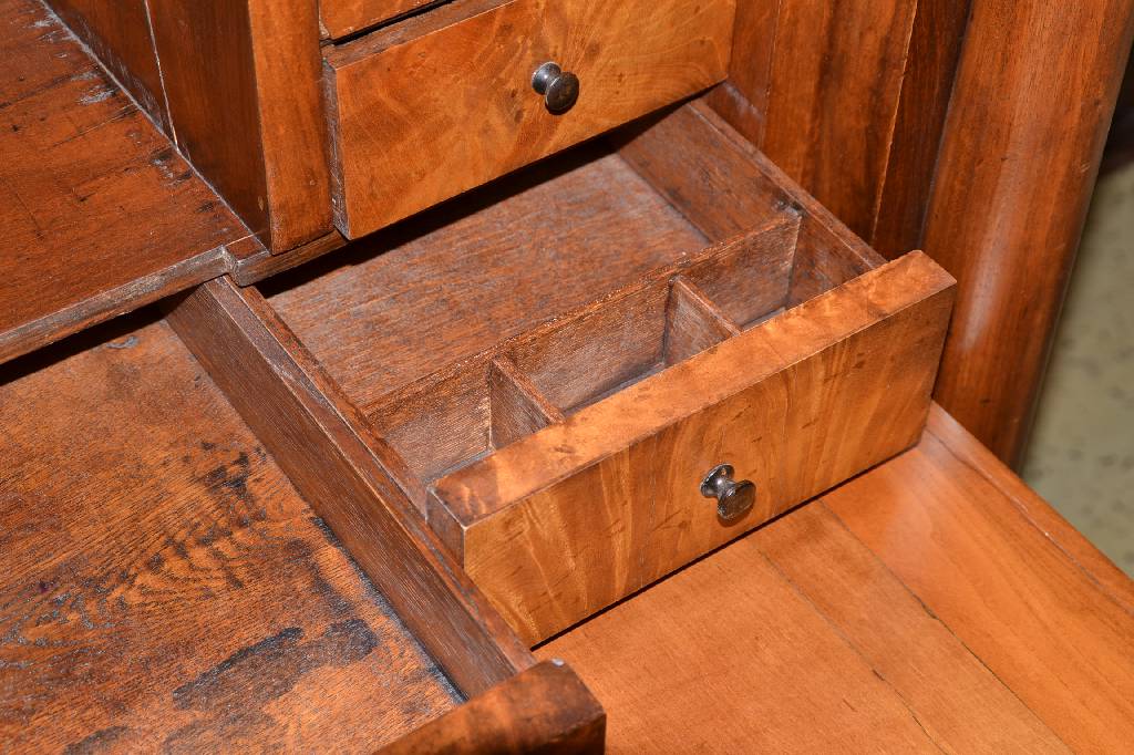 Detail a: Standsekretär, norddeutsch um 1830, Wurzelnussfurnier doppelt u. 4-fach gespiegelt verlegt, 4-schübig, Kopf 3-fach getreppt, Fuß passig, seitliche ...
