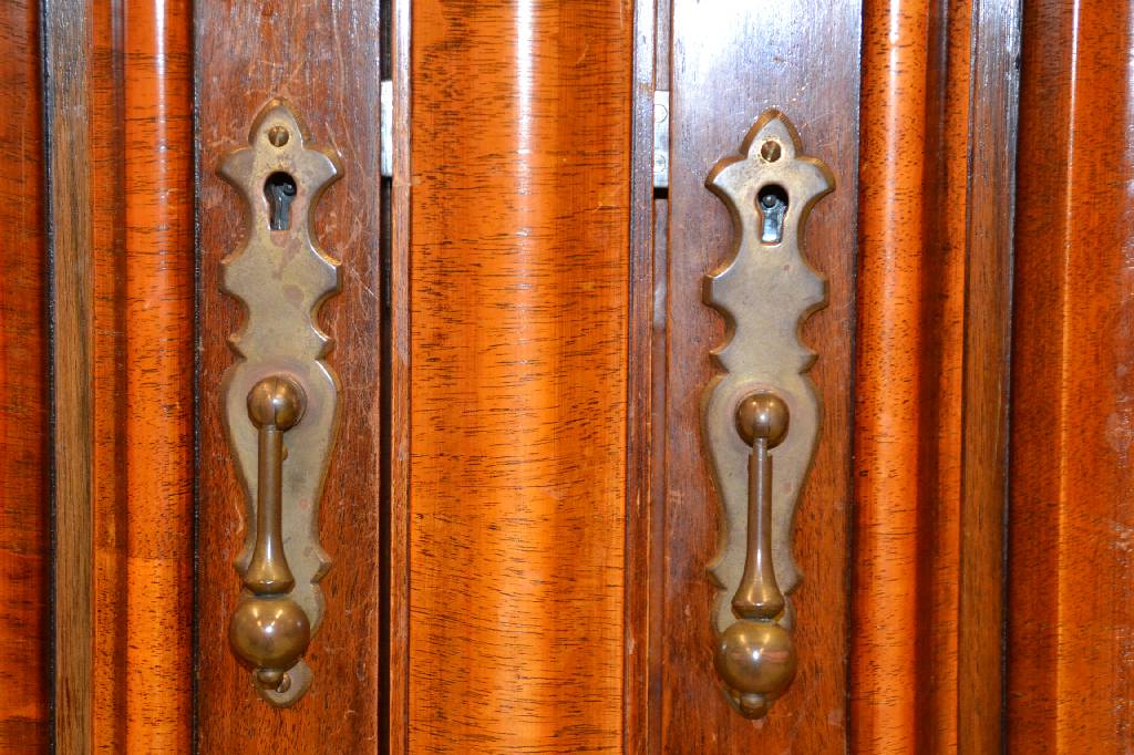 Detail b: kleiner Wellenschrank, Italien, um 1970, Nussbaum massiv z.T. quer furniert, Kopf vielfach getreppt mit Hohlkehle u. S-förmigem Profil, Türen je ...