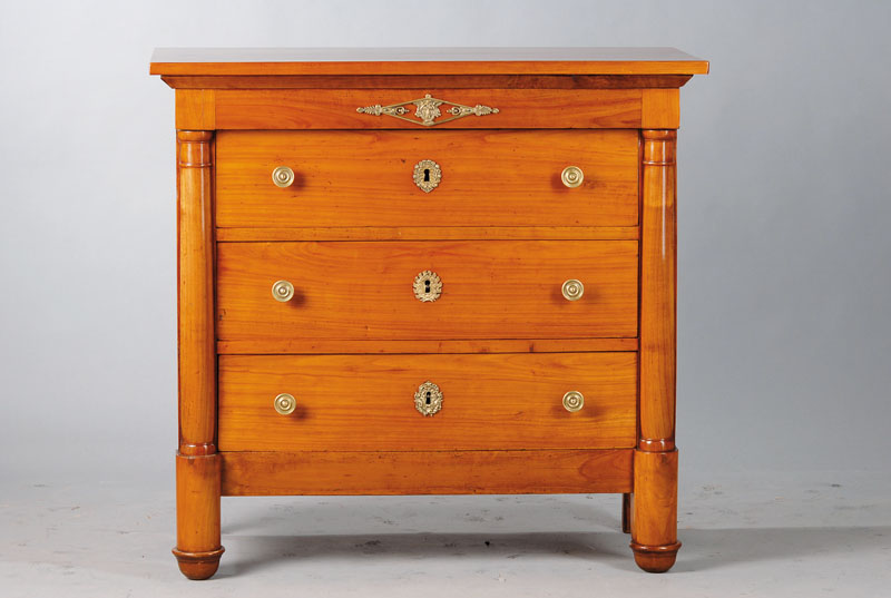 Säulenkommode, Empire um 1800, Kirschbaum massiv, seitl. Halbsäulen, Seiten je kassettiert, 3-schübig, reicher Messingbeschlag, rest., Reste alten ...