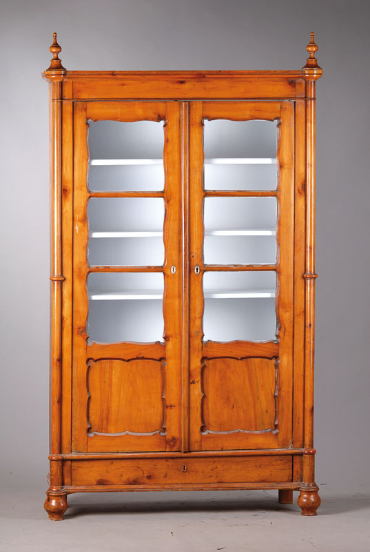 Vitrine, um 1870/80, Kirschbaum massiv z.T. furniert, Kopf mit feinen Balusterfinalen, abgekantet mit Kymaprofil, Front 2-türig, verglast, ...