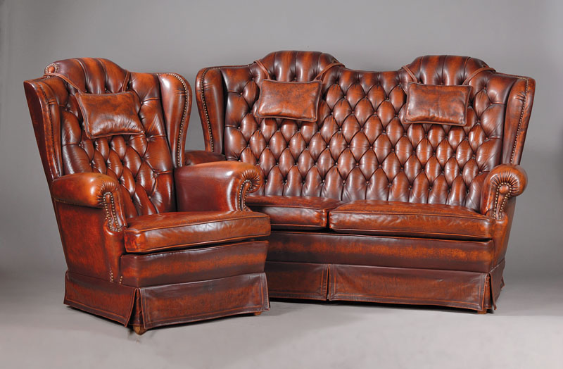 Sofa und zwei Sessel, Chesterfield, 2. Hälfte 20. Jh., Je mit Ohrenbacken, Lehnen vielfachgenoppt, Kissen aufwendig gebordet, Leder festgenagelt, ...
