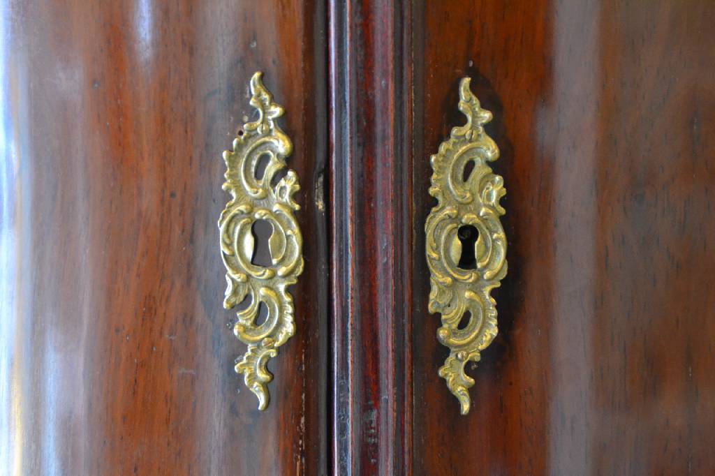 Detail b: Aufsatzschrank, Holland, um 1760, Mahagonifurnier auf Eiche, Giebel geschweift mit großzügigem Akanthusblatt-, Rosetten- u. Volutenabschluss, Kopf ...