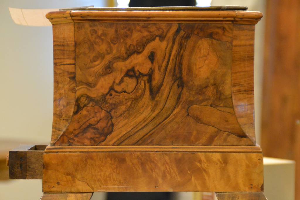 Detail b: Blumenhocker, deutsch, um 1900/10, Nußbaumfurnier, mit Metalleinsatz, obere Kanten abgeplattet, geschweifte Füße, 1- schübig, ca. 45x31x31 cm