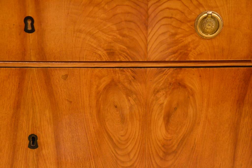 Detail a: Kommode, um 1830, Eschefurnier doppelt gespiegelt verlegt, Platte abgekantet, 3- schübig, unterer Schub u. Sockel lt. ausladend, restauriert, ...