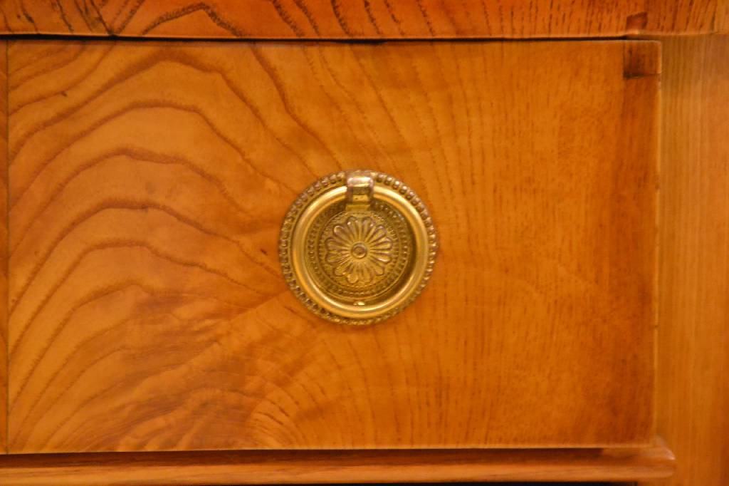 Detail b: Kommode, um 1830, Eschefurnier doppelt gespiegelt verlegt, Platte abgekantet, 3- schübig, unterer Schub u. Sockel lt. ausladend, restauriert, ...