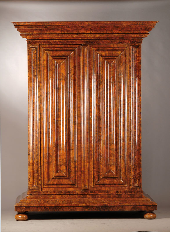 Wellenschrank, 20.Jh., Barock-Stil, Wurzelnussfurnier, Kopf weit ausladend und vielfach profiliert, Front gewellt, Seiten vereinfacht kassettiert, ...