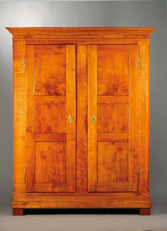 Biedermeierschrank, wohl Schwarzwald/Freiburg,1815/20, Kirschbaum massiv, regionstypische Dreifüllungsanlage, Kopf vielfach getreppt, Ecken ...