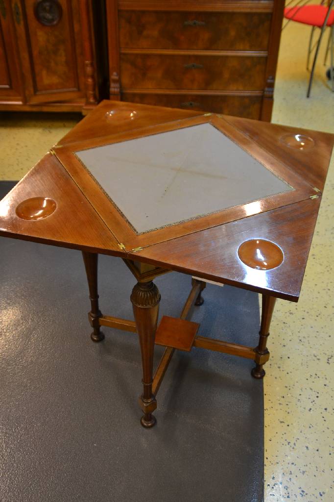Detail a: Spieltisch, deutsch um 1880/90, Nussbaum furniert, Platte drehbar u. 4-fach aufklappbar, beschnitzte Mulden für Spielsteine, Balustersäulen mit ...