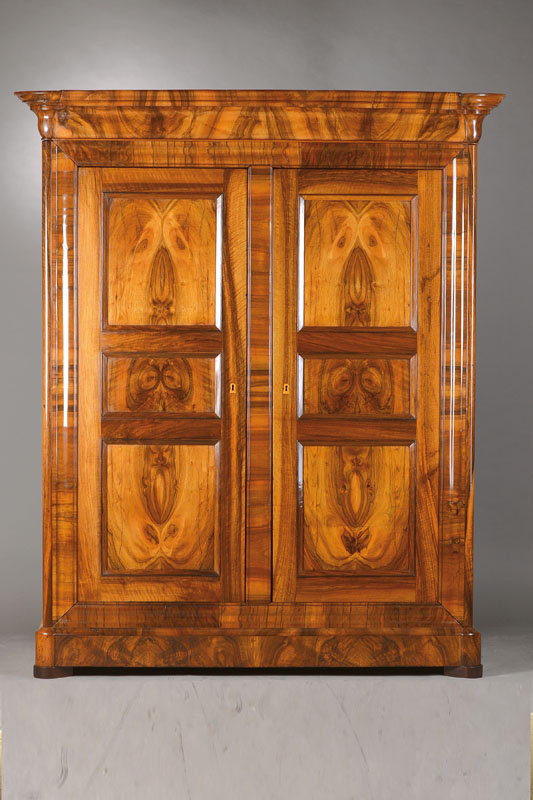 Biedermeierschrank, wohl Baden, um 1835/40, Nussbaum furniert u. massiv, vielfach mit Karnies profiliert, seitl. angesetzte Säulen, Rahmen auf ...