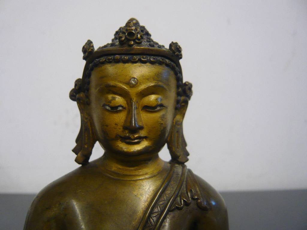 Detail a: Sitzender Buddha, Tibet, 19. Jh., Bronze, Kopf und Haare mit Resten alter Bemalung, kleiner Diamant? als drittes Auge auf der Stirn, H. 15 cm