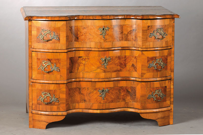 Barockkommode, norddeutsch wohl Oldenburg, um 1760/70, Nussbaum- bzw. Wurzelnussfurnier, Front doppelt geschweift u. gekröpft, 3-schübig, Füße ...