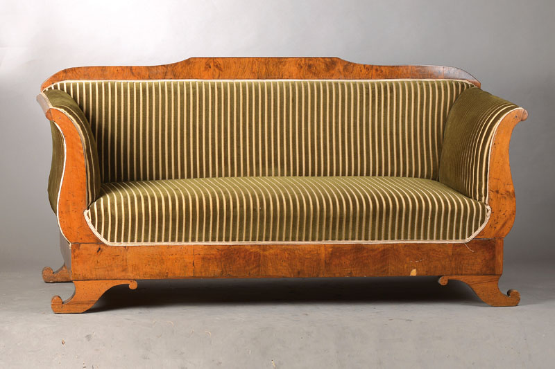 Biedermeiersofa, süddeutsch, um 1820/30, Nussbaum- u. Wurzelnussfurnier, Lehne l. geschweift, niedrige ausschweifende Füße (wohl sek.), Polsterung ...