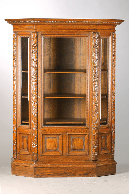 Vitrine, deutsch, um 1930, Eiche massiv, 3-seitig facettiert verglast, wuchtige Akanthusblattranken, trapezförmig, Flammleistenrahmen, Innen 3 ...