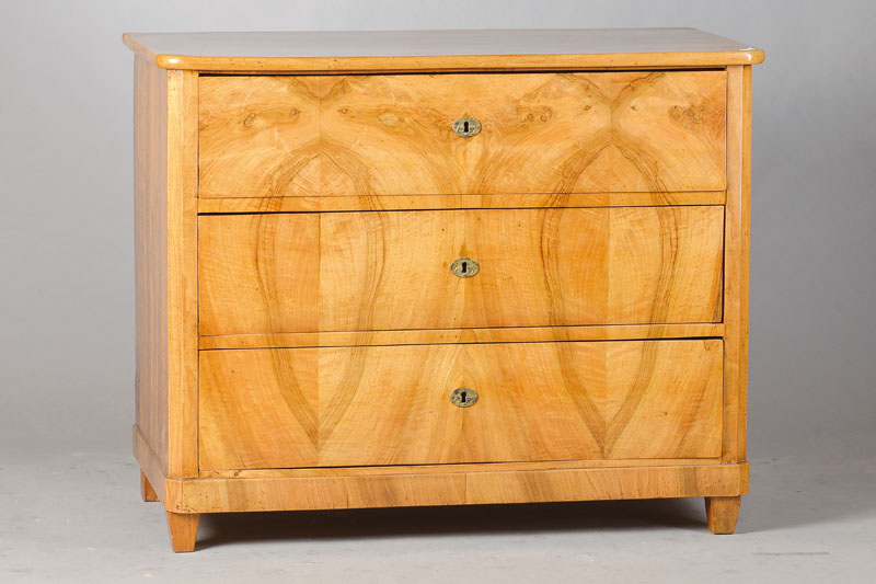 Biedermeierkommode, deutsch, um 1830/40, Nussbaum massiv z.T. doppelt gespiegelt furniert, 3-schübig, 3 orig. Schlösser, Füße u. Platte sek., ...