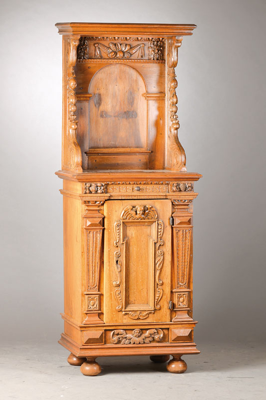 Buffet, aus Teilen des 17.Jh., im 19.Jh. umgebaut, Nussbaum massiv, Tür mit Putti- u. Knorpelornament sowie verkröpfte Flammleiste aus dem 17.Jh., ...