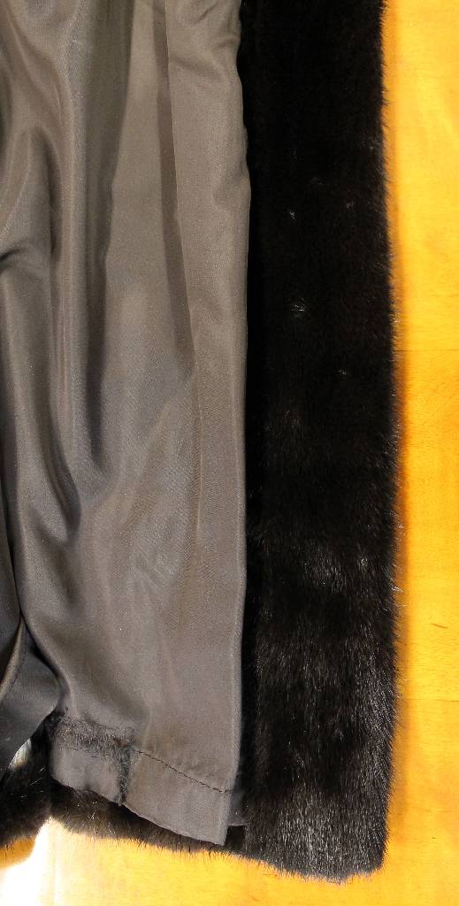 Detail c: Nerzmantel, Gr. ca. 44/46, schwarze Felle längsverarbeitet, ausgestellte Form, großer Kragen mit Zierknopf, Ärmel mit Manschetten, 2seitl. ...