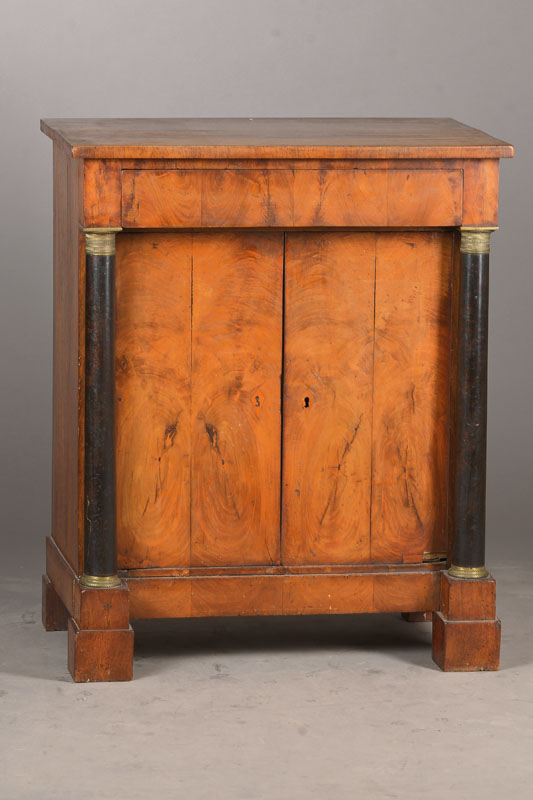 Halbschrank, wohl Rheinland, um 1820/30, Nussbaum furniert u. massiv, Weichholzkorpus, einÜberbauschub, gestützt von 2 geschwärzten Vollsäulen ...