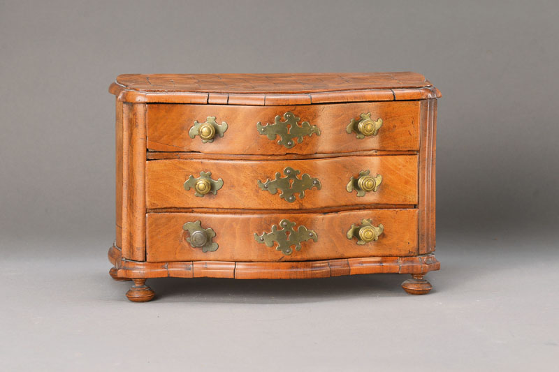 Barocke Modellkommode, wohl Niederrheinisch, Gegend Köln, um 1760, Nussbaumfurnier auf Weichholzkorpus, 3-schübig, allseitig geschweift, Platte ...