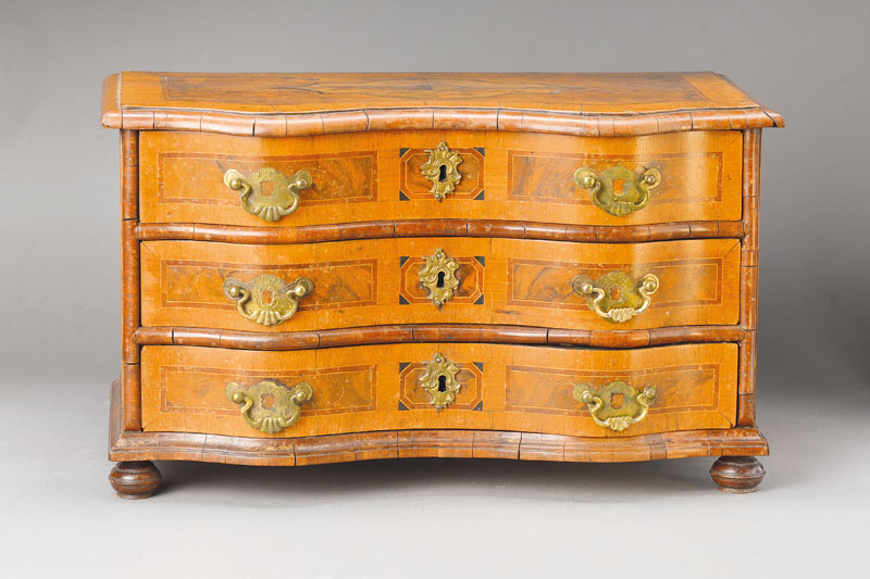 Miniaturkommode, wohl westdeutsch, um 1750, Nussbaum- bzw. Wurzelnussfurnier auf Weichholzkorpus, Pflaumenbänder u. Ahornfilets, vielfeldriger ...