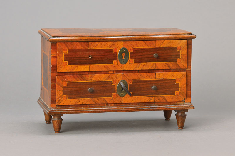 Barockmodellkommode, süddeutsch, um 1750/60, Nussbaumfurnier vielfach auf Kreuzfuge verlegt, geometrisierende verkröpfte Felder in Ahornfilets mit ...