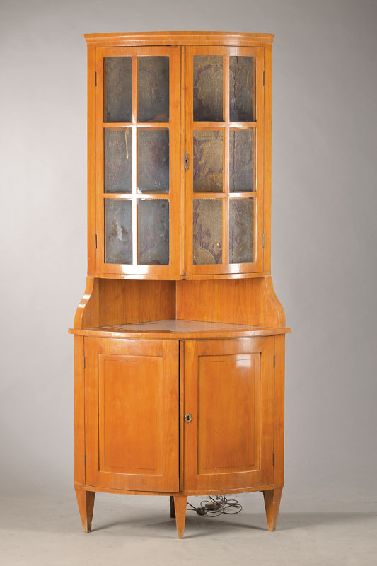 Eckvitrine, deutsch, um 1900, im Biedermeierstil, Kirschbaumfurnier auf Weichholzkorpus, Unterbau 2-türig auf konischen Vierkantfüßen stehend, ...