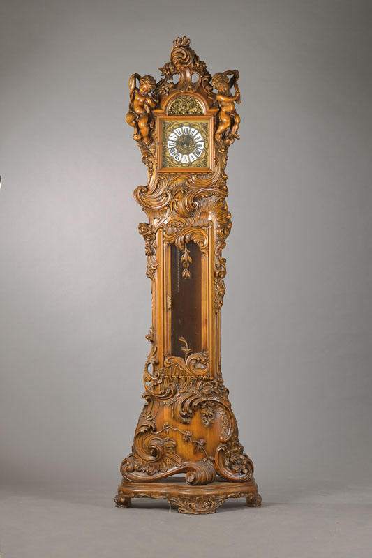 Standuhr mit Westminsterschlag, deutsch um 1970, Holzgehäuse mit dreiseitigen großvolumigen Schnitzereien, schwungvolle Voluten, ausladener Sockel, ...