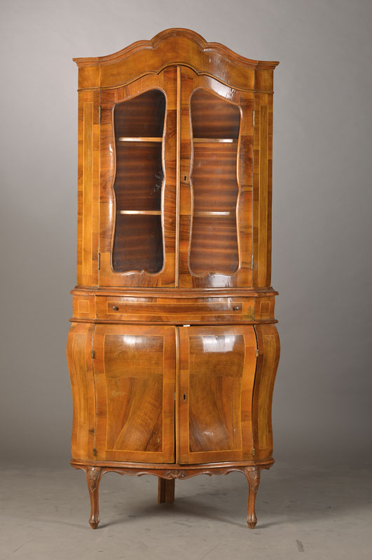 Aufsatzvitrine, wohl Italien, 60/70er Jahre, im Barockstil, Nussbaumfurnier, Korpus vielfach bombiert u. geschweift, Unter- u. Oberteil je 2-türig, ...