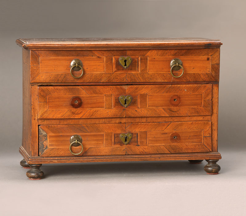 Miniaturkommode, wohl Hessen, um 1740/50, Nussbaum massiv, helle Partien in Kirschbaum furniert, 2-schübig, oben zum Truhenkasten umgebaut, 3 Ringe ...