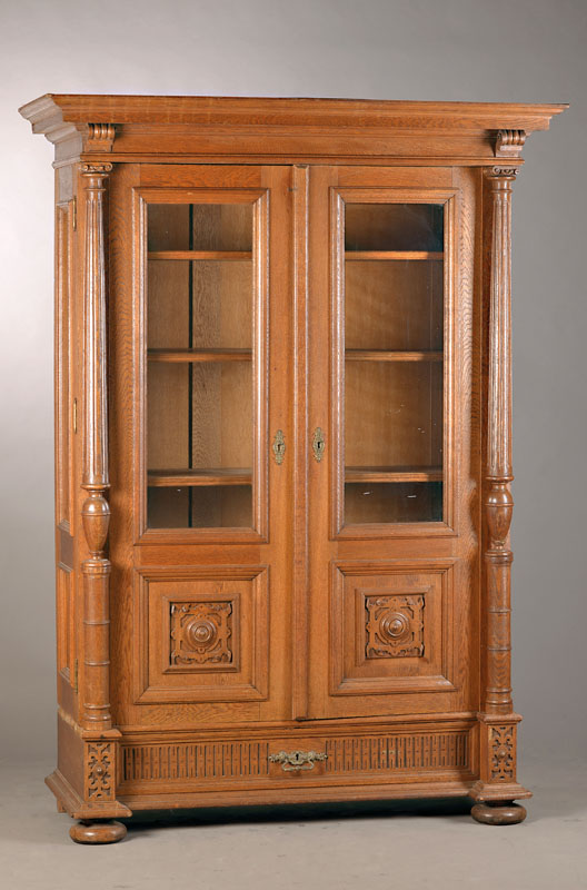 Gründerzeitvitrine, deutsch, um 1880/90, Eiche massiv, 2-türig, verglast, Kassetten mit Rollwerkschnitzerei, Säulenvorbau, Sockelschublade, orig. ...